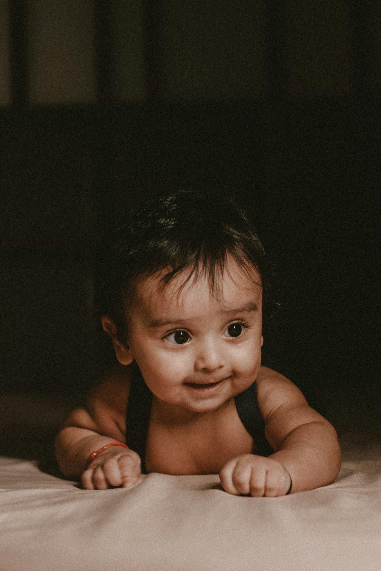 a baby laying on a bed looking at the camera